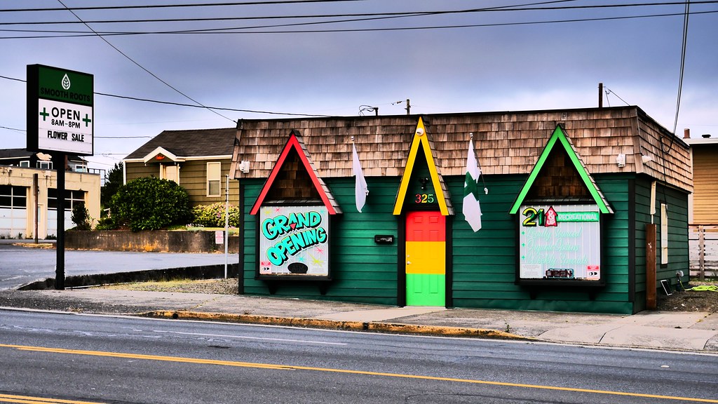 Small green shop with colorful triangular roofs and a Grand Opening sign