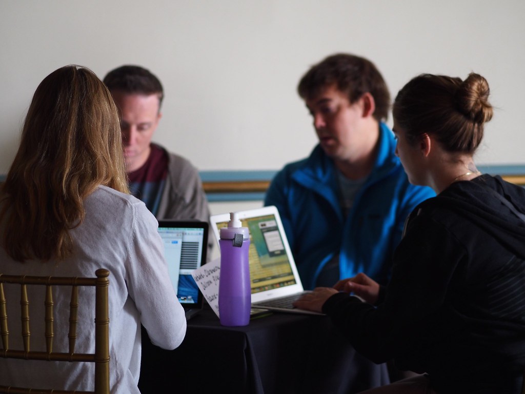 Four people working on laptops at a table